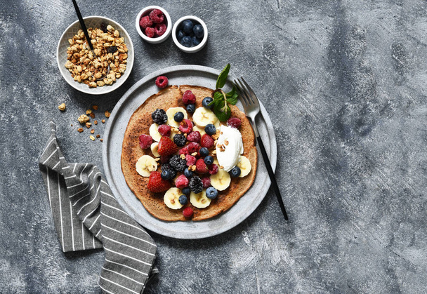 Crepe with berries and yogurt for breakfast. Breakfast on the kitchen table top view. - Foto, Imagen
