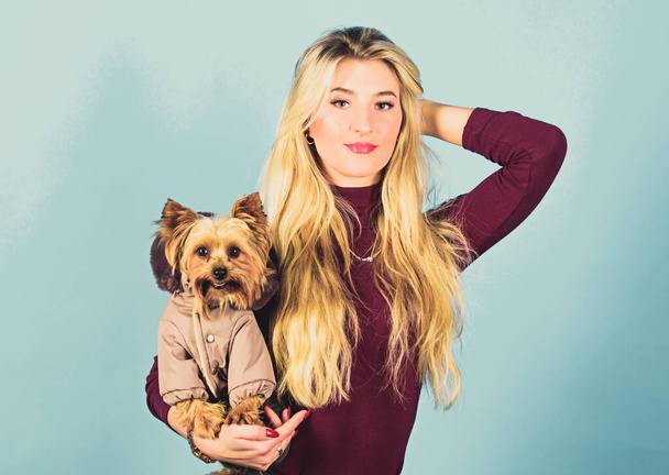 Girl adorable blonde hug little dog in coat. Apparel and accessories. Pet supplies. Dressing dog for cold weather. Which dog breeds should wear coats. Woman carry yorkshire terrier. Dogs need clothes - Foto, Imagem