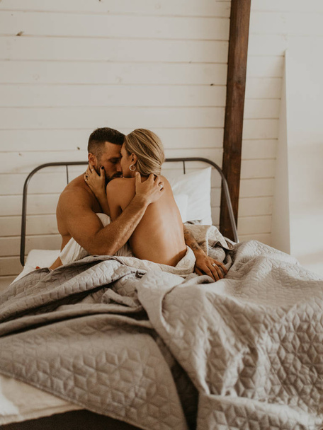 Beautiful loving couple kissing in bed - Фото, изображение