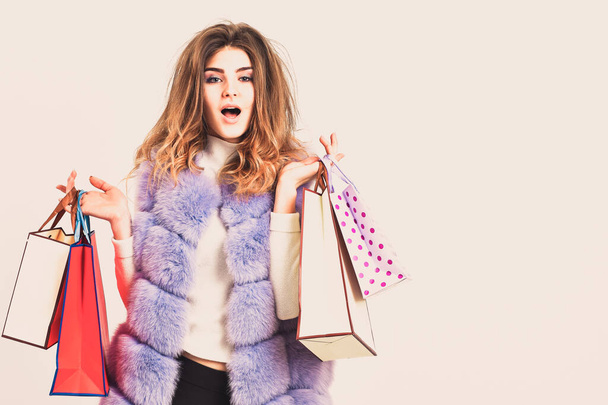 Girl makeup furry violet vest shopping white background. Woman shopping luxury boutique. Lady hold shopping bags. Discount black friday. Shopping and gifts. Fashionista buy clothes on black friday - 写真・画像