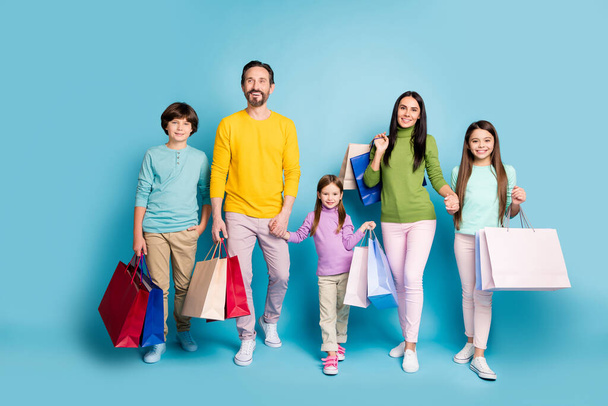 Full length body size view of nice attractive lovely glad cheerful family carrying bags new things clothes spending day black Friday isolated on bright vivid shine vibrant blue color background - Photo, image