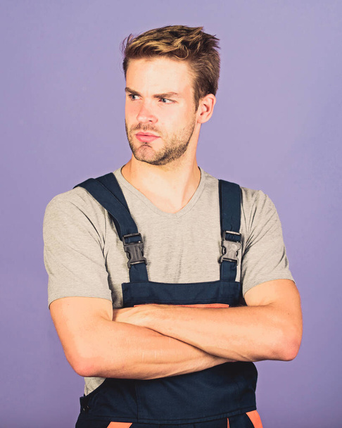 Troubleshoot and fix faulty electrical switches. Assemble and set up machinery or equipment. Thoughtful repairman. Handsome repairman. Worker violet background. Man repairman builder in work clothes - Photo, Image