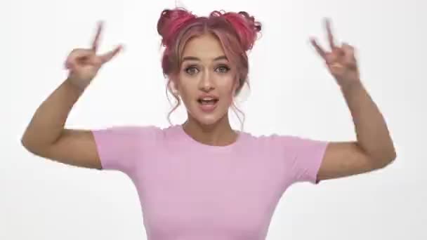 Une jeune femme positive fait un geste de paix avec les deux mains tout en clignant des yeux isolé sur fond blanc
 - Séquence, vidéo