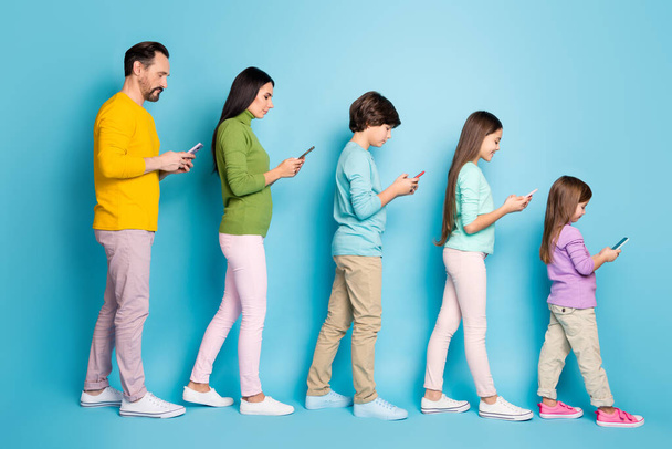 Full length body size profile side view of nice attractive focused cheerful big full family pre-teen kids using 5g internet online isolated on bright vivid shine vibrant blue color background - Foto, imagen