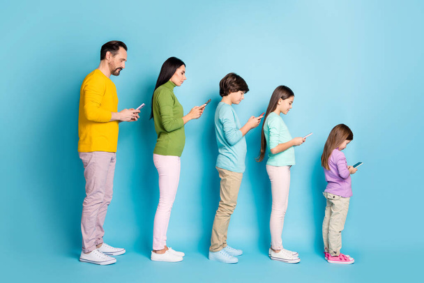 Full length body size profile side view of nice attractive addicted focused big full family using digital device browsing internet online isolated on bright vivid shine vibrant blue color background - 写真・画像