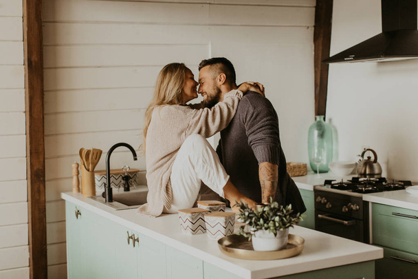 Beautiful couple in love kisses in the kitchen - Zdjęcie, obraz