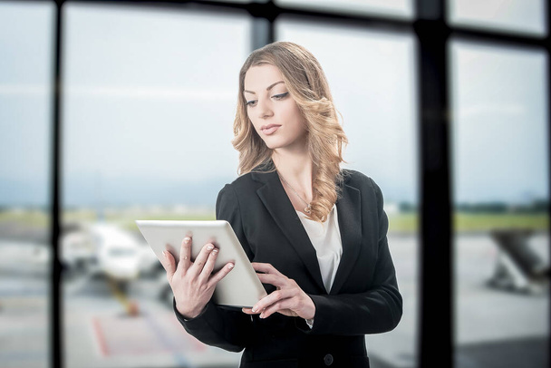 ブロンド美しいビジネス女性作業ノートパソコンで待っている間に彼女のフライトで空港 - 写真・画像
