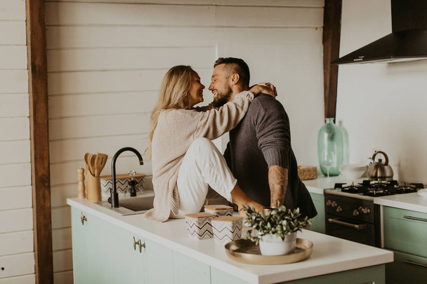Beautiful couple in love kisses in the kitchen - Фото, изображение