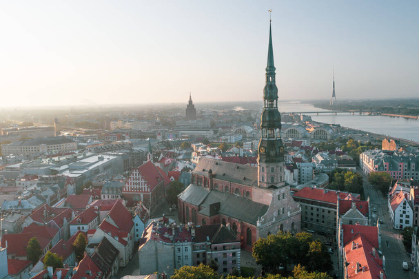 Luchtfoto van vliegende drone panorama naar St. Peter 's Church en de oude stad op de achtergrond van de Daugava rivier en het centrum op een prachtige vroege zonsopgang (serie) - Foto, afbeelding