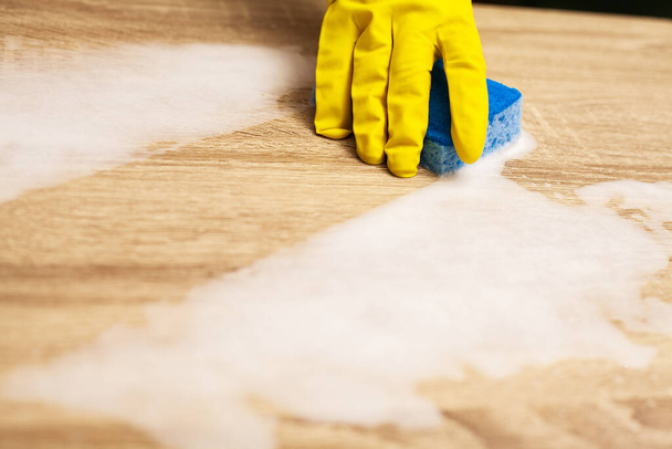 Pracownik stosujący gąbkę do czyszczenia drewnianego stołu - Zdjęcie, obraz