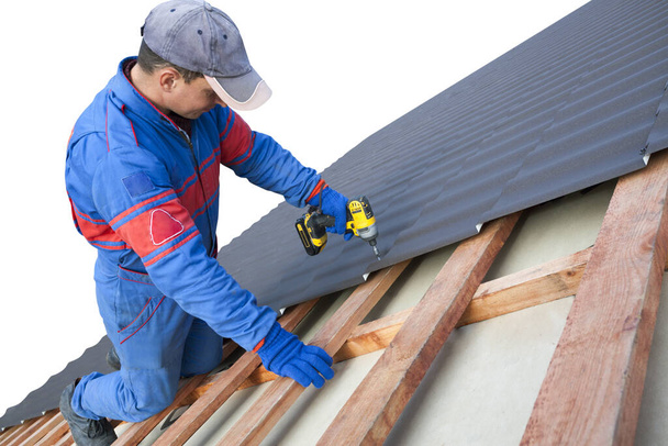 Man werknemer maakt gebruik van een boormachine om een kap metalen dakbedekking baan met schroeven bevestigen. - Foto, afbeelding