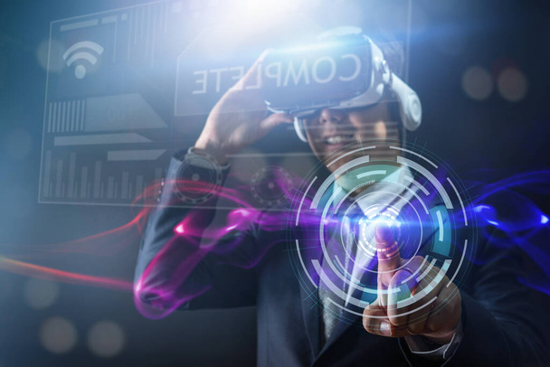 El concepto de innovación tecnológica y empresarial digital, el hombre de negocios que usa gafas de realidad virtual se juega por la noche con el suave zumbido azulado. - Foto, Imagen