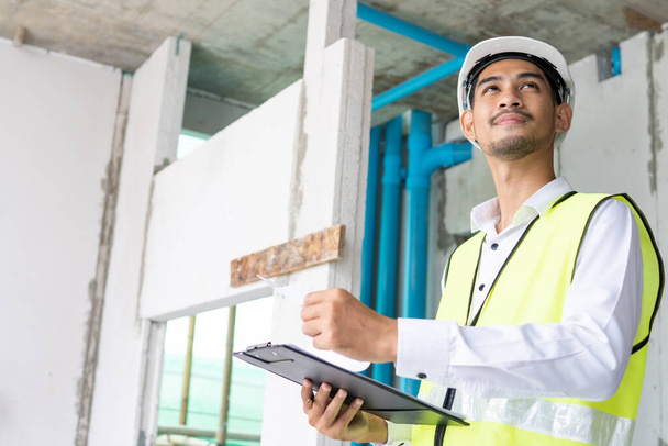 Inspecteur tenant la planche à papiers et vérifiant le bâtiment à rénover, ingénieur arpenteur regardant sur le chantier de construction  - Photo, image