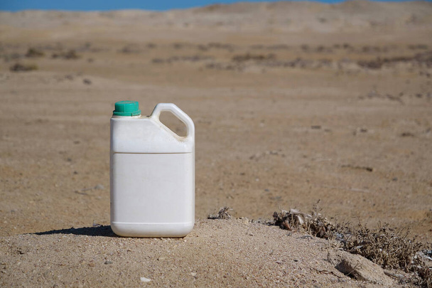 Белая пластиковая бутылка стоит в пустыне
 - Фото, изображение
