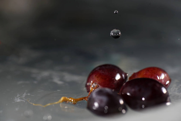 Кучки винограда в ледяной воде с красочными вспышками, сфотографированными в студии
 - Фото, изображение