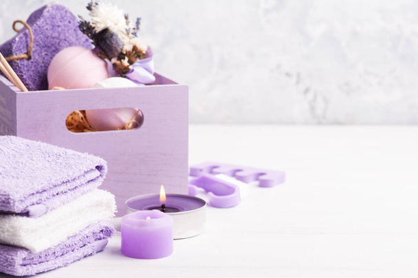 Bombas de baño de aroma, piedra pómez púrpura y lavanda en SPA arrengement en caja de madera. Toallas, velas púrpuras encendidas con espacio para copiar
 - Foto, Imagen
