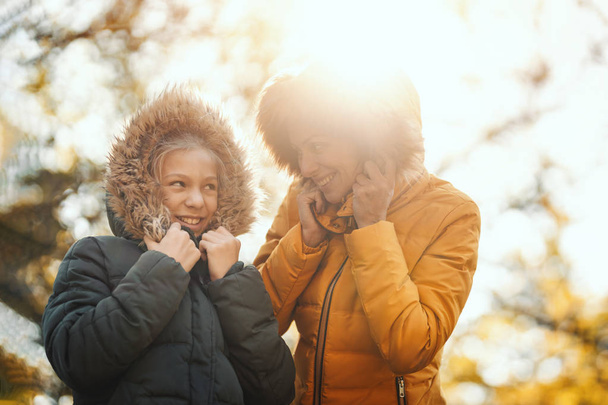 mooie moeder en haar gelukkig tiener dochter zijn glimlachen en plezier hebben in het park in zonsondergang. - Foto, afbeelding