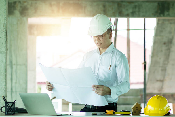Chytrý inženýr při pohledu na modrý tisk a kontrole průběhu práce na staveništi  - Fotografie, Obrázek