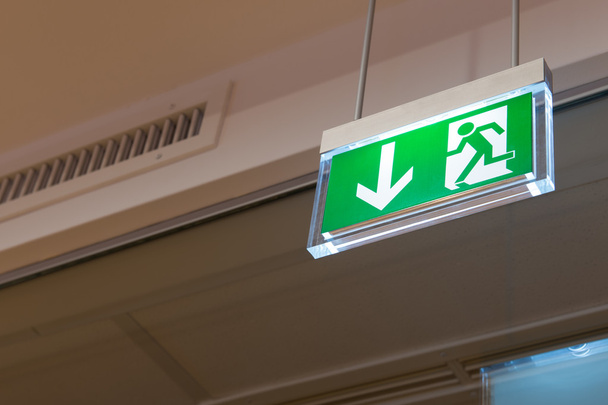Green illuminated exit sign on ceiling - Photo, Image