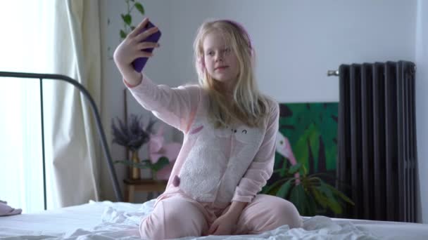 vida moderna de la generación Z. adolescente en pijama y auriculares en la habitación en la cama escucha música desde un teléfono inteligente
. - Metraje, vídeo