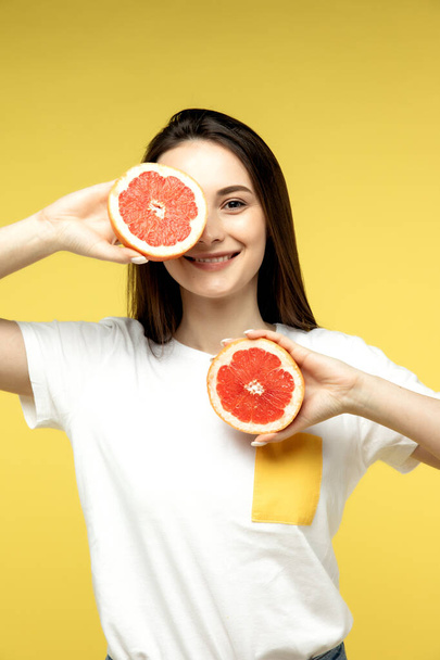 Young asian girl holding a grapefruit over isolated orange background - Foto, Imagem