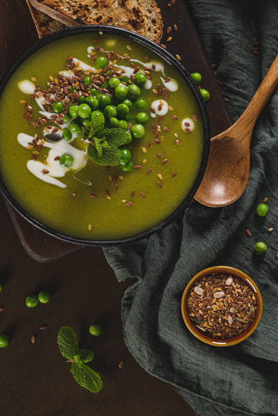 Green pea soup with linseed and pumpkin and sunflower seeds on a rustic kitchen countertop. - Foto, imagen