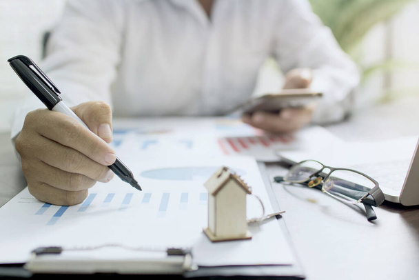 homem de negócios ou banqueiro verificando gráfico de finanças de lucro de imóveis e venda de casa na mesa
  - Foto, Imagem