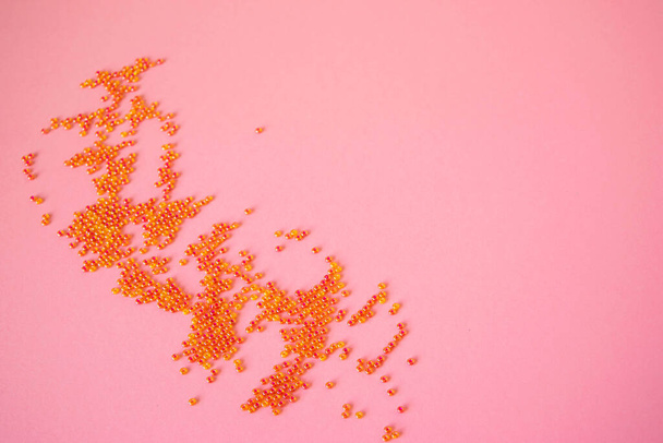 Hrst roztroušených růžových korálků na pastelově světle růžovém pozadí. Fotografie předmětu pro design s kopírovacím prostorem v minimálním stylu, šabloně pro psaní nebo textu. - Fotografie, Obrázek
