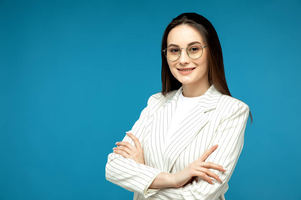 Portrait of cousin woman smiling with arms crossed on blue background - Photo, image