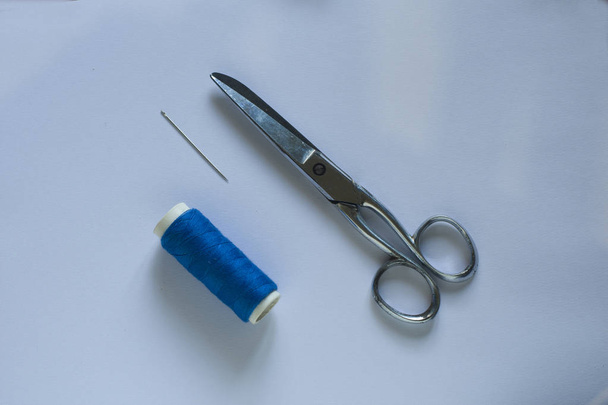 Sininen kulutuspinta saksilla ja neula vaaleansinisellä pöydällä
 - Valokuva, kuva