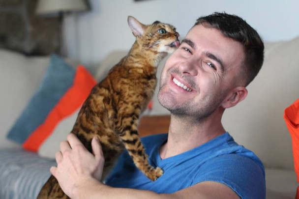 Экзотический кот играет со своим красивым владельцем
 - Фото, изображение