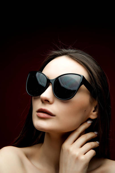 Portrait of beautiful woman in heart-shaped sunglasses. Pretty girl in hoody posing on bright background. Free space for text. - Foto, immagini