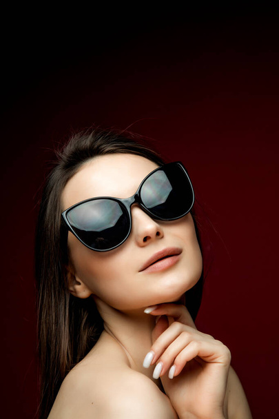 portrait of young beautiful slim woman in sexy dress with sensual lips in studio wearing sunglasses smiling and posing - Photo, image