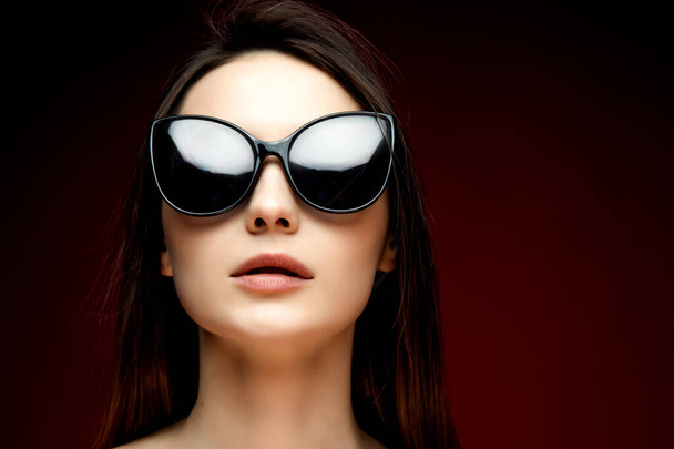 fashion model in sunglasses, beautiful young woman. lstudio shot, red background - Фото, зображення