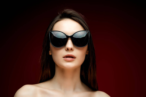 portrait of young beautiful slim woman in sexy dress with sensual lips in studio wearing sunglasses smiling and posing - Fotó, kép