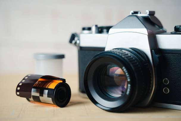 Régi Slr film kamera és egy tekercs film fából készült háttér. - Fotó, kép