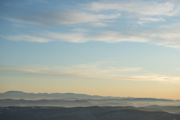 Belle vue sur la chaîne de montagnes partiellement recouverte de neige juste avant le coucher du soleil. Ciel partiellement orange au coucher du soleil
 - Photo, image