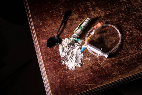 Drugsprobleem concept. Drugsspuit en narcotische attributen op houten tafel. Aankoop, bezit en verkoop van drugs is wettelijk strafbaar. Creatieve kunstwerken decoratie - Foto, afbeelding
