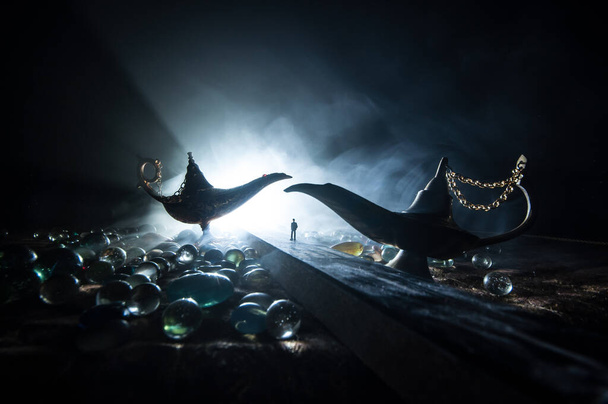 Lampada dei desideri concetto. Silhouette di un uomo in piedi in mezzo alla strada in una notte nebbiosa con gigante antico Aladdin arabo notti genie stile lampada ad olio. Decorazione artistica creativa
 - Foto, immagini