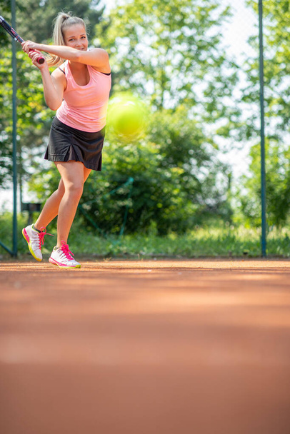 Top view of attractive young woman tennis player serving on a clay tennis court.  - Foto, immagini