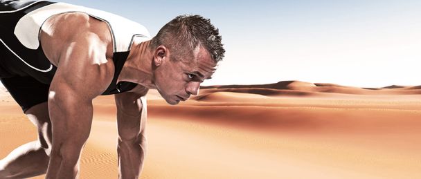 extreme atleet loper man in de uitgangspositie buiten in woestijn op hete zomerdag. - Foto, afbeelding