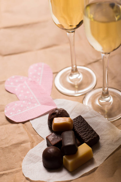 Chocolate candies on a hearts shaped napkins and two glasses of wine - Photo, Image
