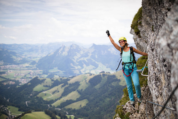 Bonita escaladora femenina en vía ferrata escalando en una roca en los Alpes suizos - Foto, imagen