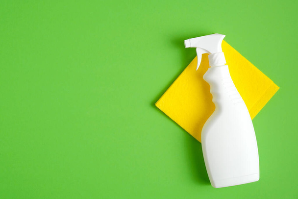 Cleaning spray bottle on yellow napkin over green background. Flat lay, top view. Cleaning services concept. - Foto, Imagem