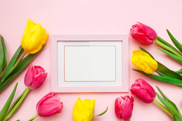 Happy Women's Day, Mother's Day greeting card concept. Pink tulips flowers and photo frame on pink background, copy space for your text. Top view, flat lay - Fotó, kép