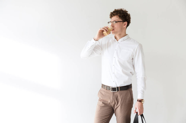 Handsome confident young curly haired businessman wearing white shirt standing infront of isolated background, drinking coffee - Photo, image