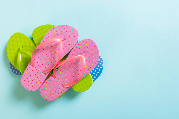 A lot of colored flip flops on blue background. Top view with copy space. - Photo, Image