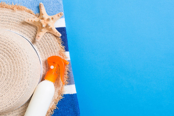 Summer beach flat lay accessories. Sunscreen bottle cream, straw hat, towel and seashells on colored Background. Travel holiday concept with copy space. - Fotoğraf, Görsel