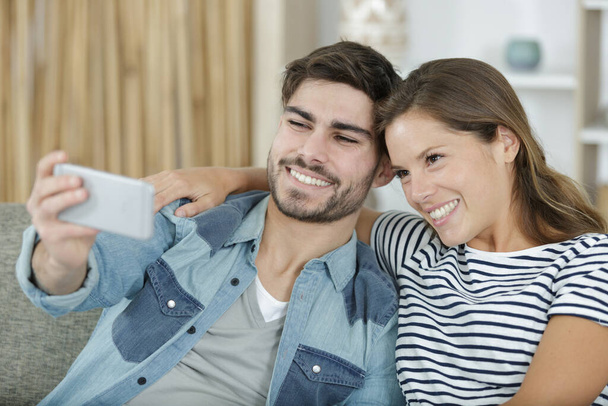 young happy couple taking selfie on sofa - Foto, Imagem