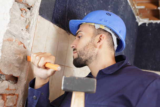 man wearing with a hammer on wall - Φωτογραφία, εικόνα